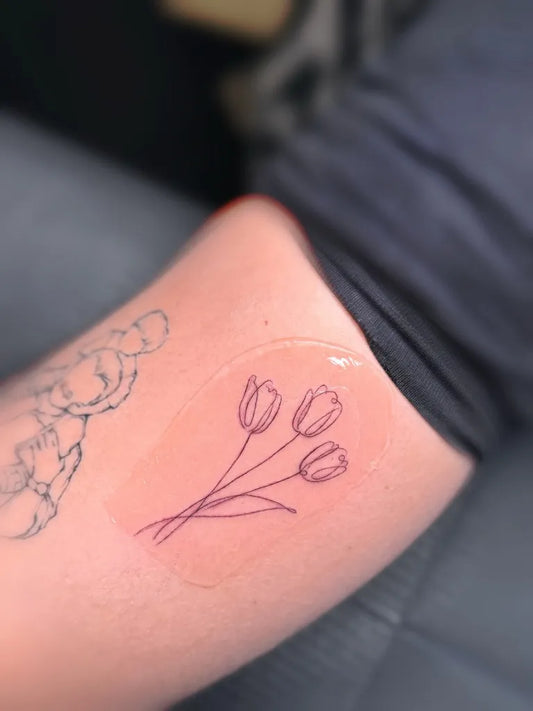 Small Fine Line Three Tulips Tattoo on Women Thigh by @elizatattooamsterdam