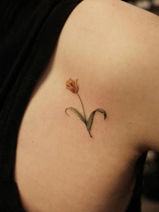 Small Fine Line Tulip Tattoo on Women Shoulder by @inkconcept_studio