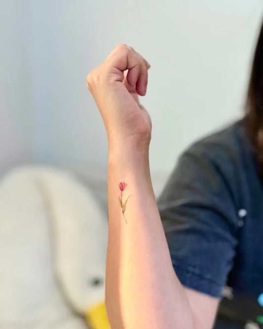 Small Fine Line Tulip Tattoo on Women Wrist by @jollyland.ink