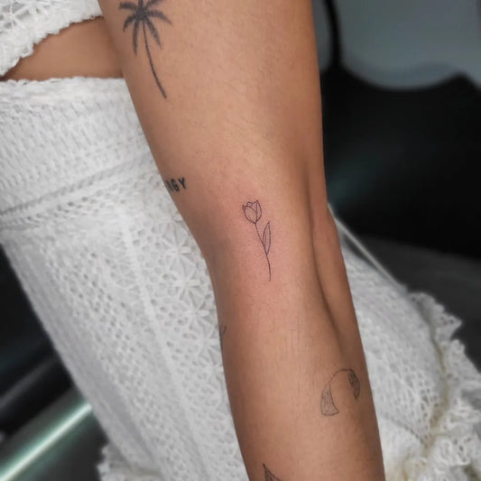 Small Fine Line Tulip and Palm Tattoo on Women Thigh by @alexherndzstudio