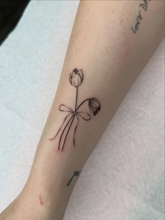 Small Fine Line Tulips with Bow Tattoo on Women Arm by @ti.mikhael