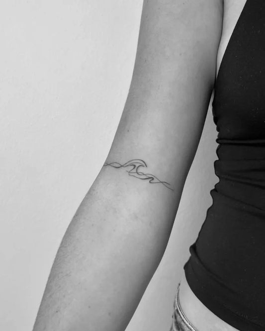 Small Fine Line Wave Tattoo on Women Arm by @madelinehatrick.tattoo