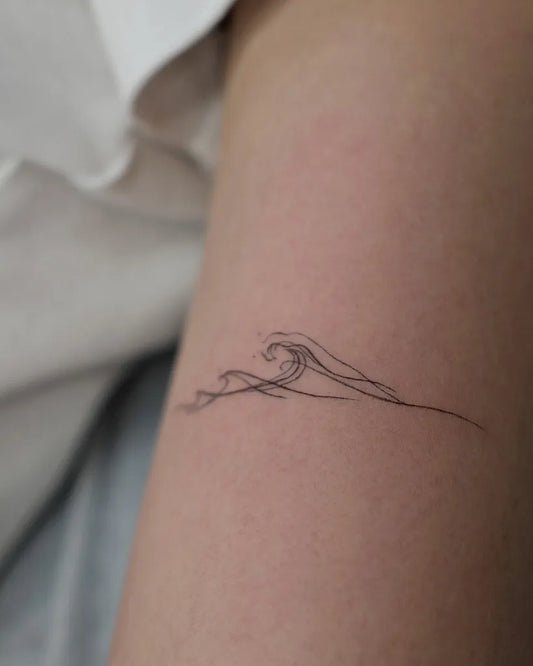 Small Fine Line Wave Tattoo on Women Arm by @seung_tattoo