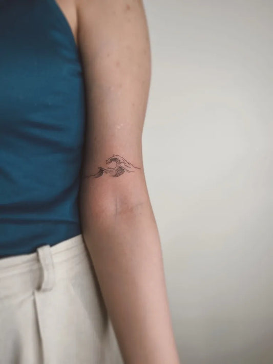 Small Fine Line Wave Tattoo on Women Arm by @tattfarangis