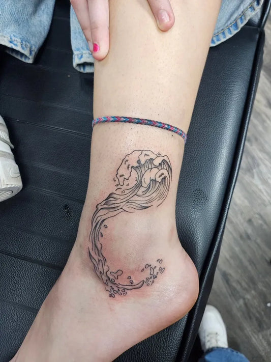 Small Fine Line Wave and Flowers Tattoo on Women Ankle by @inkyuli_tattoo