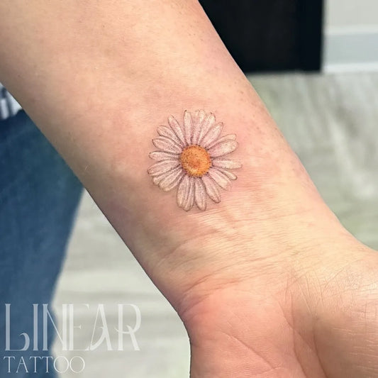 Small Fine Line White Daisy Tattoo on Women Wrist by @christina.lineartattoo