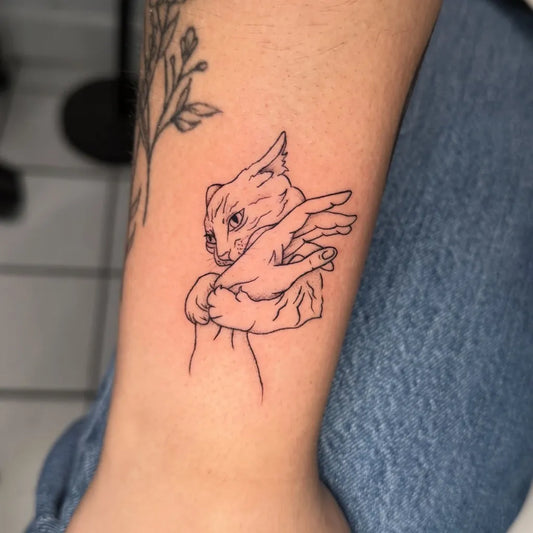 Small FineLine Cat in Human Hand Tattoo on Women Arm by @juliag.tattoo