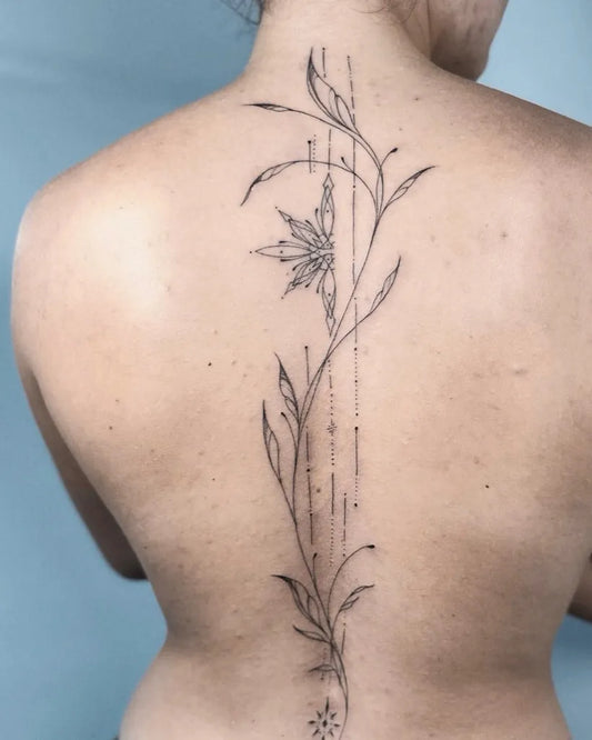 Small FineLine FoliageAndSnowflake on Women Spine Tattoo by @nothingwildtattoo