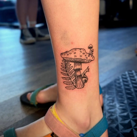 Small FineLine Mushroom Snail Fern on Women Ankle Tattoo by @burnedheartstattoos