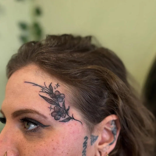 Small Floral Flowers and Leaves on Women Face Tattoo by @tattoos.by.marie.k