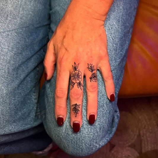 Small Floral Flowers and Leaves on Women Fingers Tattoo by @goldenhourtattoo