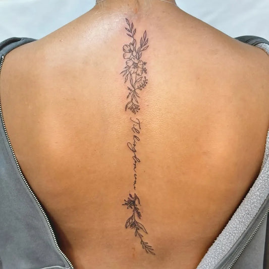 Small Floral Script with Flowers Women Spine Tattoo by @lucykellytattoos