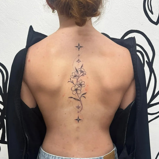 Small Floral Spine Flowers and Stars on Women Spine Tattoo by @shoresidetattoo