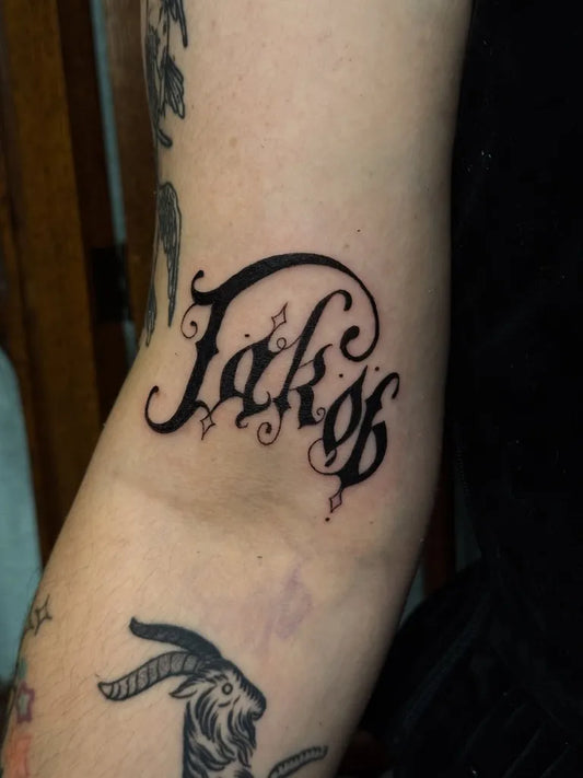 Small Gothic Fancy Word Tattoo on Women Arm by @poison.well