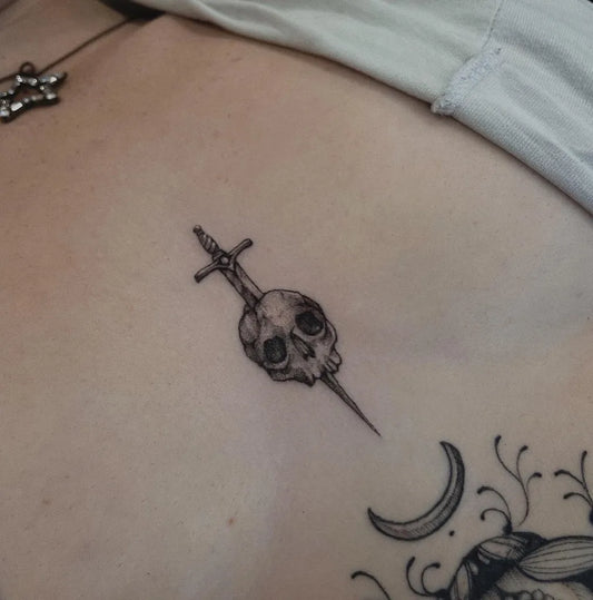 Small Gothic Skull Sword Crescent on Women Sternum Tattoo by @breadfei.ce_