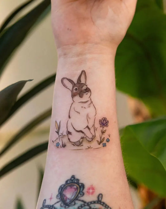 Small Illustrative Bunny with Flowers Tattoo on Women Wrist by @chonify.inks