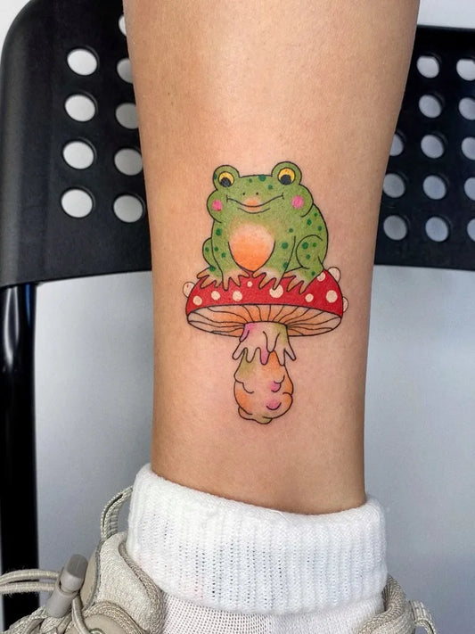 Small Illustrative Frog on Mushroom Tattoo on Women Ankle by @kotastiia