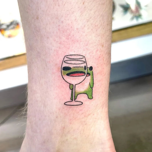Small Illustrative Frog with Wine Glass Tattoo on Women Ankle by @buoythefishlover