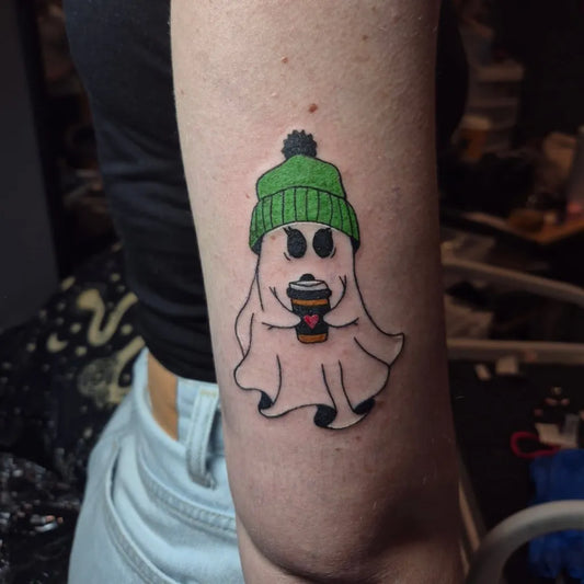 Small Illustrative Ghost with Coffee Green Hat Tattoo on Women Arm by @inkedvoidtattoos