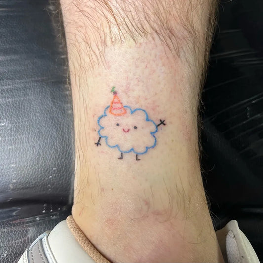 Small Illustrative Happy Cloud with Party Hat Tattoo on Men Leg by @babbygail_doodles