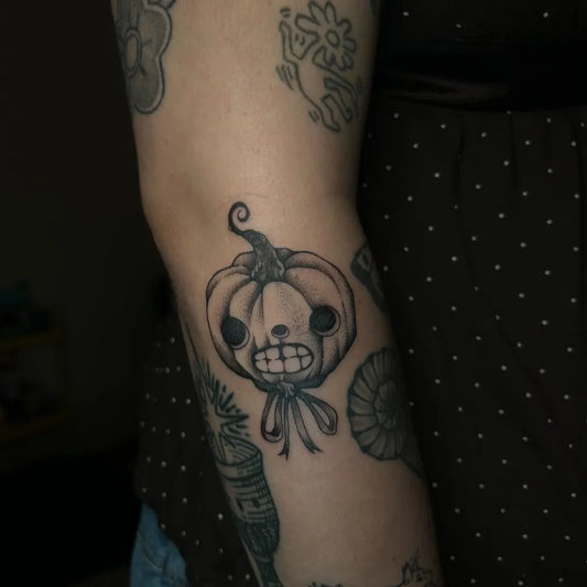 Small Illustrative Jack o lantern with Ribbon Tattoo on Women Arm by @stargirltattoos