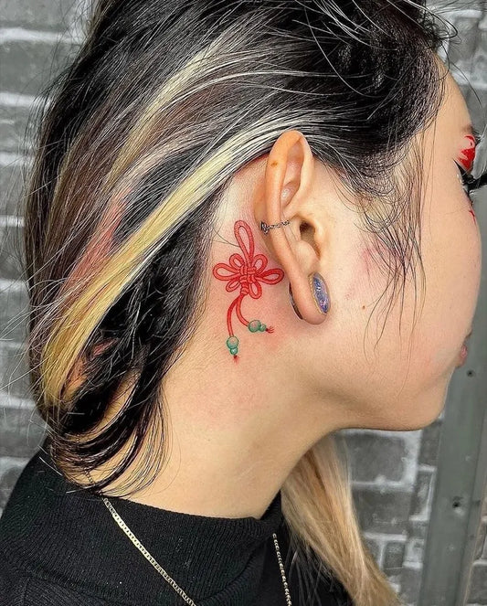 Small Illustrative Red Flower Knot with Stem Tattoo on Women Behind the Ear by @enso.ink.sandiego
