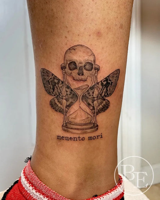 Small Illustrative Skull Hourglass Memento Mori on Women Leg Tattoo by @brenna.eagan