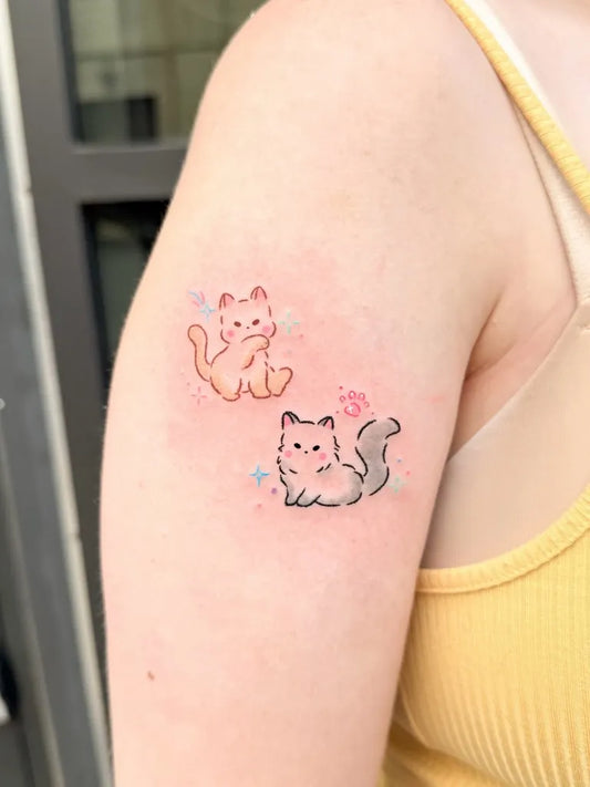Small Illustrative Two Cats Tattoo on Women Upper Arm by @hyanggi_pastel