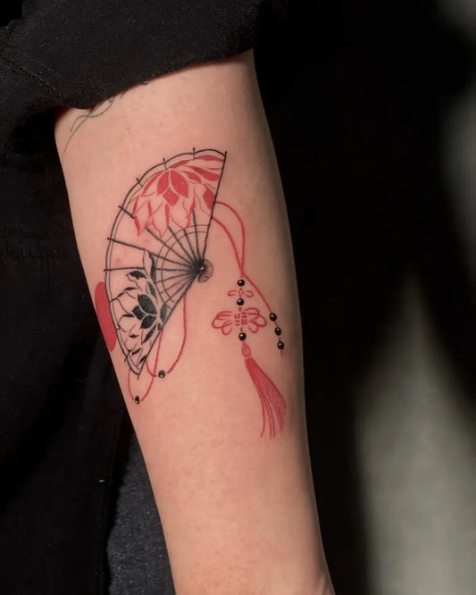 Small Japanese Fan with Tassels and Flowers on Women Arm Tattoo by @fantattoo.art