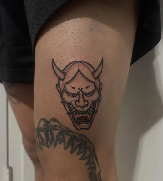 Small Japanese Oni Mask on Women Thigh Tattoo by @ink.walker