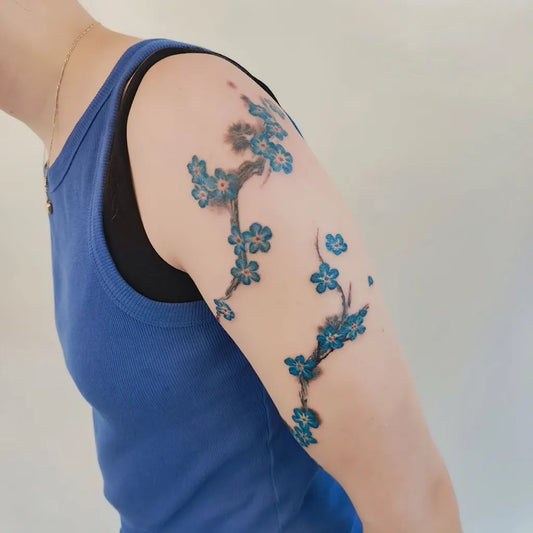Small Japanese Style Blue Cherry Blossom Branches on Women Arm Flower Tattoo by @lea_tattoo