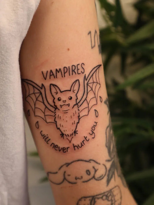 Small Linework Bat with Text and Dog Tattoo on Women Arm by @lovemore.tattoo