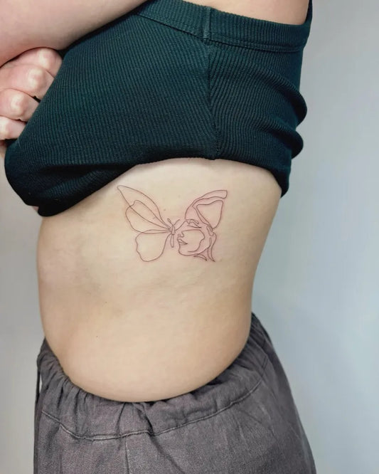 Small Linework Butterfly and Face Tattoo on Women Rib by @kj.finelinetattoos