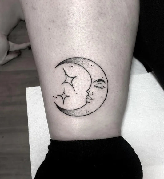 Small Linework Crescent Moon with Face and Stars Tattoo on Women Thigh by @laurbo_ink