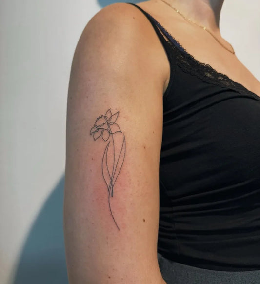 Small Linework Daffodil Tattoo on Women UpperArm by @aphra_ink