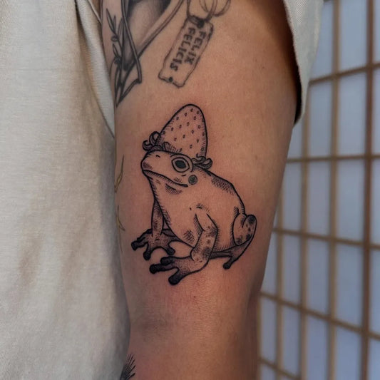 Small Linework Frog Wearing Strawberry Hat Tattoo on Women Arm by @chelsbellsinks