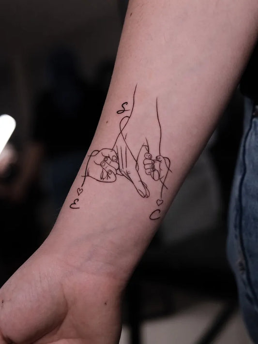 Small Linework Handholding Children Family Tattoo on Women Wrist by @onurzeytin.ink