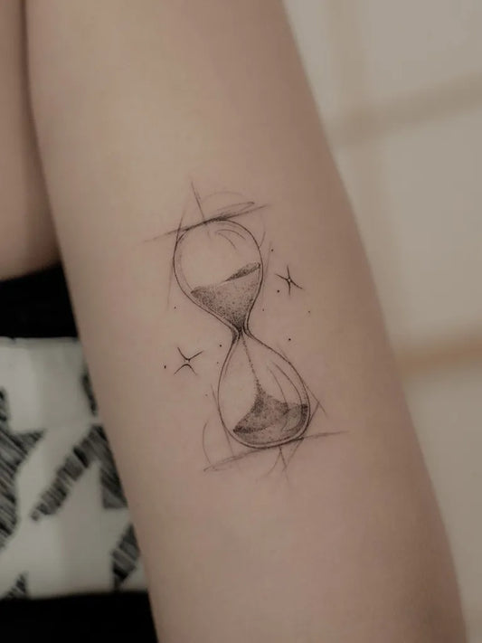 Small Linework Hourglass with Stars Tattoo on Women Arm by @jk.tattoo