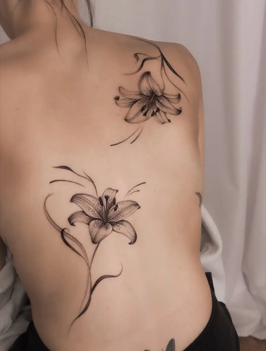 Small Linework Lily Flowers on Women Back Tattoo by @bluerain.tattoo