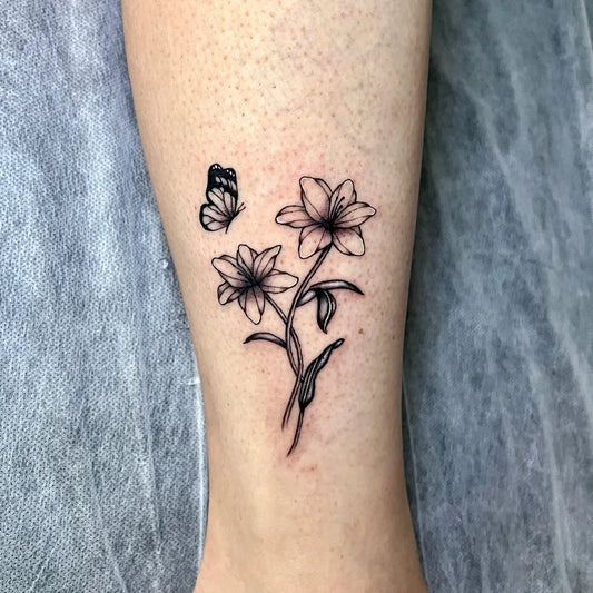 Small Linework Lily and Butterfly on Women Leg Flower Tattoo by @chromeink_tattoo
