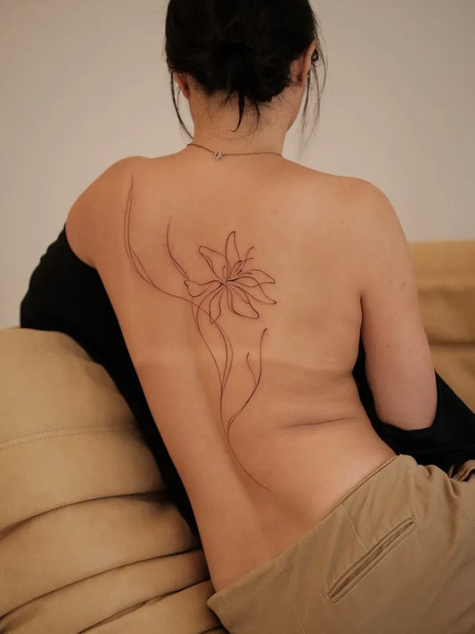 Small Linework Lily on Women Back Tattoo by @mjs_tats