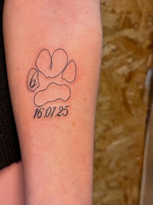 Small Linework Paw Print with Date Tattoo on Women Arm by @erininks_
