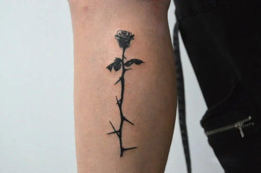 Small Linework Rose with Thorns on Women Thigh Tattoo by @tia_497