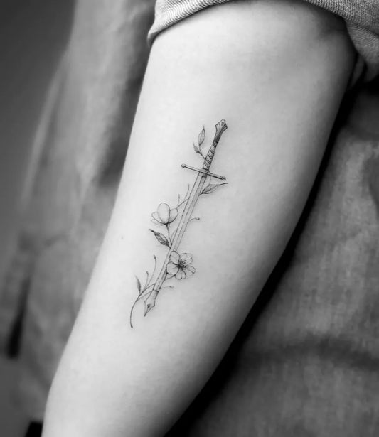 Small Linework Sword and Flowers on Women Arm Tattoo by @shan.6tattoo