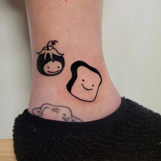 Small Linework Tomato Face and Toast on Women Ankle Tattoo by @spoopy.ca