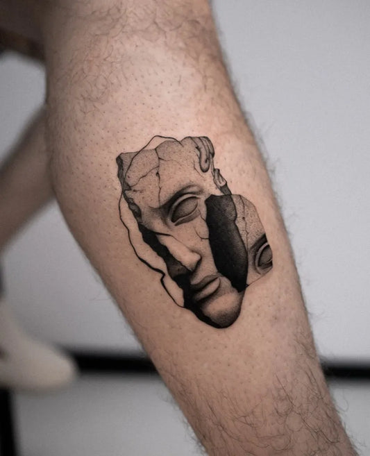 Small Micro Realism Broken Sculpted Face on Men Leg Tattoo by @julianvlaar
