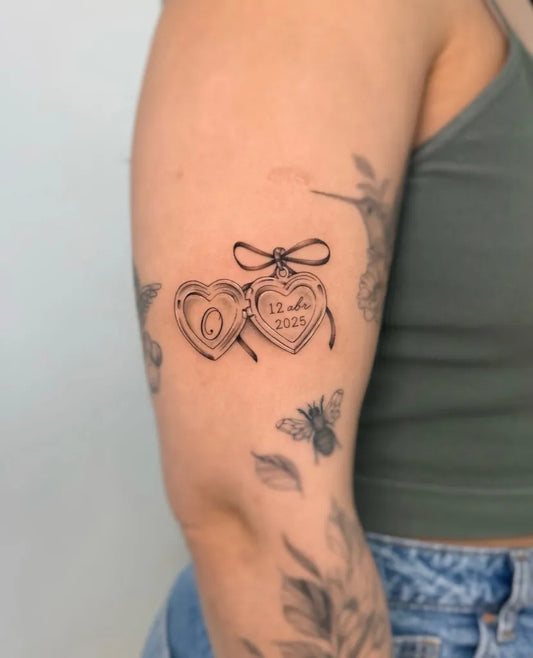 Small Micro Realism Heart Locket with Ribbon and Date on Women Arm Tattoo by @deborahleall