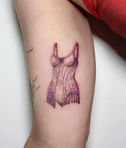 Small Micro Realism Pink Corset on Women Arm Tattoo by @nataliamateo.tattoo