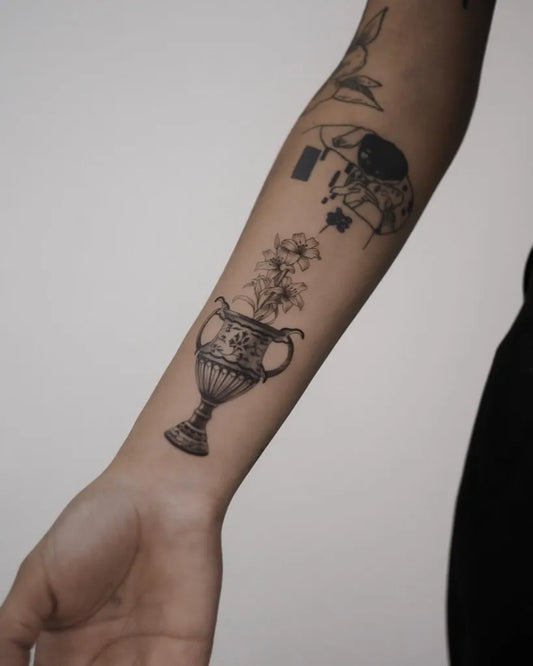 Small Micro Realism Vase with Flowers and Bird on Women Arm Tattoo by @rebustattoo_