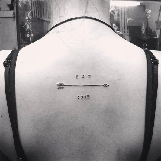 Small Minimalist Arrow Letters Year Tattoo on Women Back by @jello_t
